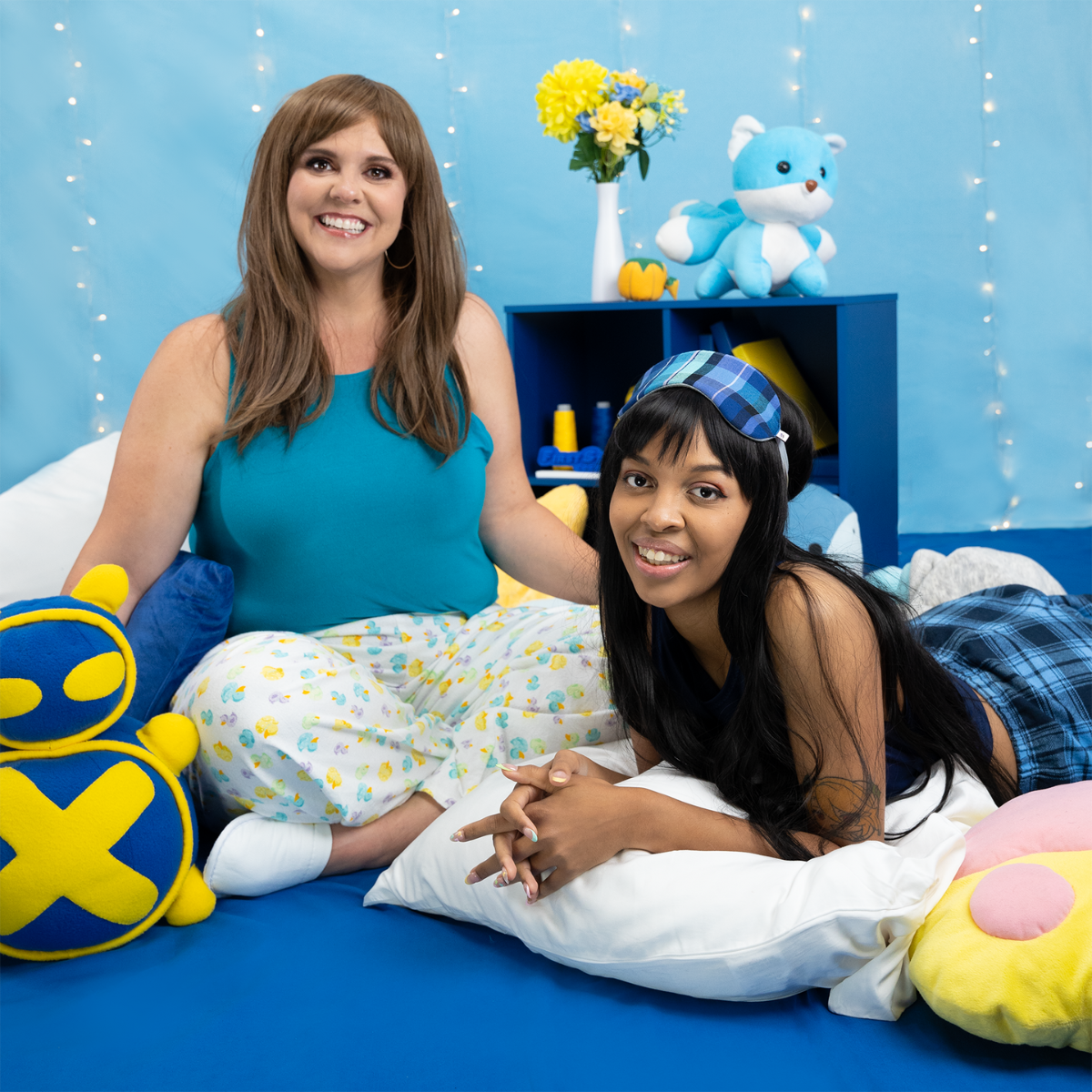 Two female models (sizes J and C) sitting on the ground wearing the Sleeveless Crop Top with pajama pants. The size C model, hyliancream, is propped on a pillow.