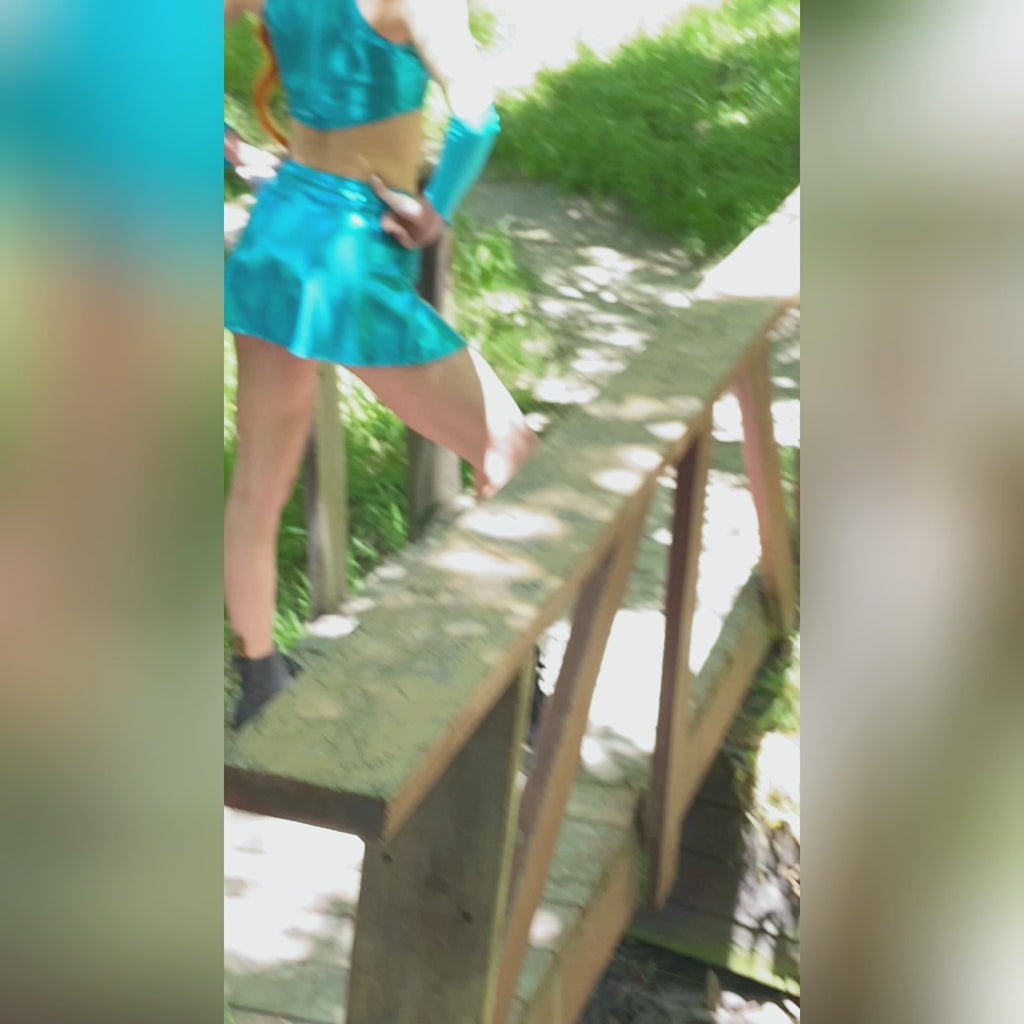 Short video of a female cosplayer posing in the Winx Club Bloom sewing pattern. She is outside in nature with fairy-like plants and scenery.